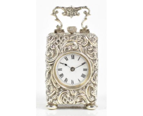 HENRY MATTHEWS; an Edward VII hallmarked silver cased dressing table clock with repoussé detail and swing handle, raised on f