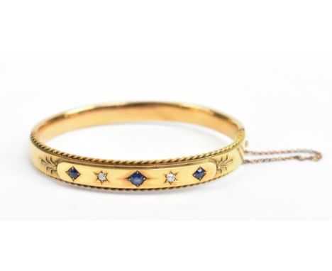 A 15ct yellow gold hinged snap bangle with three sapphires and two diamonds to the raised platform, internal width 5.7cm, app