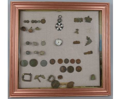 A framed display of metal detector finds, entitled "Waterloo", including coins, bullets, enamalled wreath, buckles, thimble, 