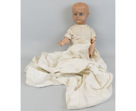 A gesso and carved wooden head doll, with fixed glass eyes and painted wooden jointed body, unmarked, 54cm high