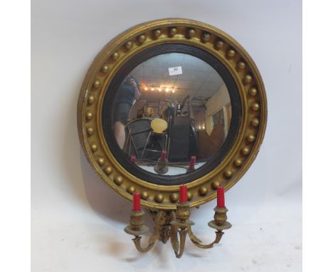 A regency giltwood convex mirror with beaded border and three branch candelabra. H-68cm, Diameter-55cm 