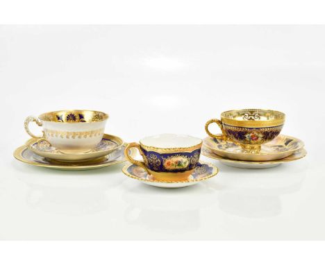 E. BARKER FOR ROYAL WORCESTER; a hand painted trio, painted with floral sprays inside gilt painted and jewelling on a puce an