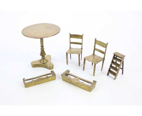 A small collection of miniature brass furniture including a tilt-top table, two chairs, a step ladder and two fenders.
