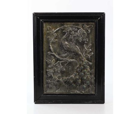 An Arts &amp; Crafts sheet pewter wall plaque relief decorated with a peacock, having twenty-one enamel cabochons making the 