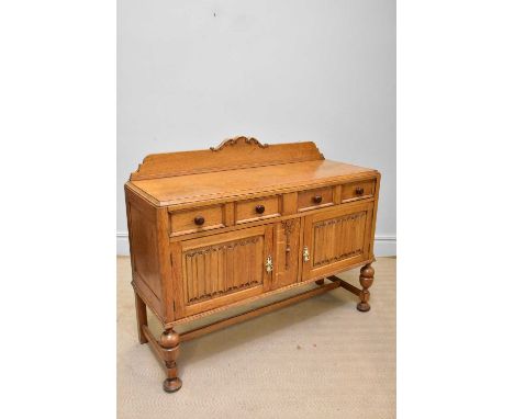 A light oak sideboard with raised arched back above two drawers and two doors, with linenfold decoration, width 136cm, depth 