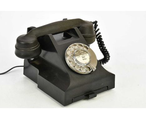 A black bakelite rotary telephone.