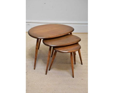 ERCOL; a medium elm nest of three graduated pebble tables on turned column legs. 