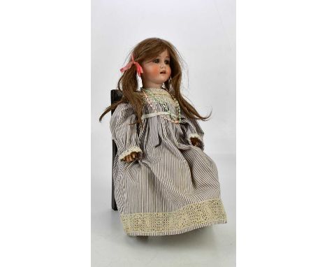 MAX HANDWERCK; a German bisque headed doll with glass sleeping eyes and articulated limbs, and associated later chair.