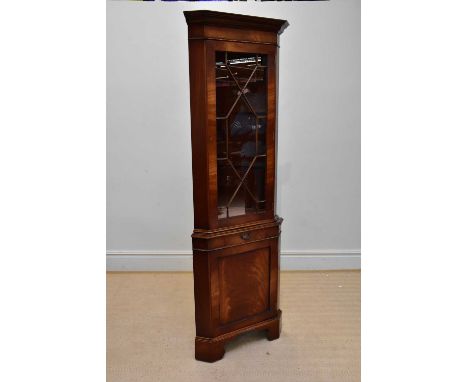 A reproduction mahogany freestanding corner cupboard with glazed door above drawer and panel door, on bracket feet.