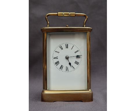 A French brass carriage clock, with a shaped handle and insight platform escapement, the rectangular dial with Roman numerals