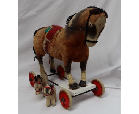 A Steiff pull along horse with well loved mohair body on white rimmed red wheels, 49cm long together with two donkeys