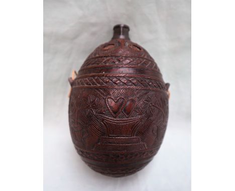 A coconut flask, carved with a unicorn and lion pierced hearts, vases of flowers, a face etc, 13cm long