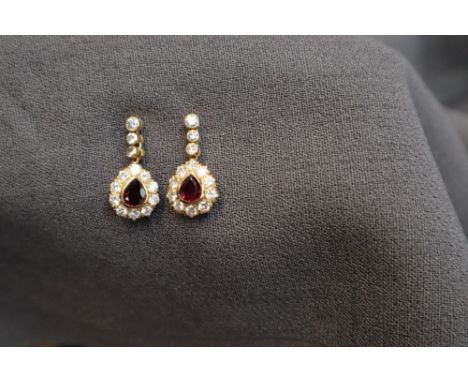 A pair of 18ct yellow gold ruby and diamond drop earrings, each set with a central pear shaped ruby approximately 7mm x 5mm, 