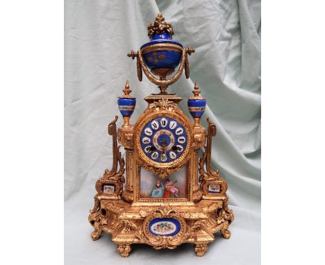 A 19th century French gilt spelter and porcelain plaque inset mantle clock, with a central swag mounted urn, flanked by a pai