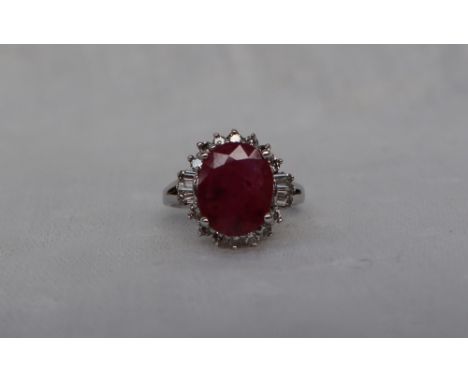 A Ruby and diamond cluster ring, the central oval faceted ruby approximately 11mm x 9mm surrounded by baguette and round bril