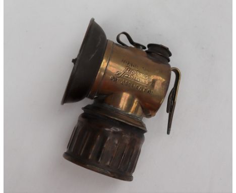 An early 20th century Justrite brass miners helmet lamp, with a 6.5cm diameter reflector, 10cm high 