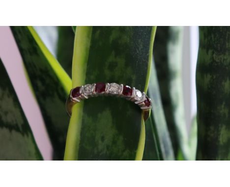 A ruby and diamond half eternity ring set with four rubies and three round brilliant cut diamonds to an 18ct yellow gold shan