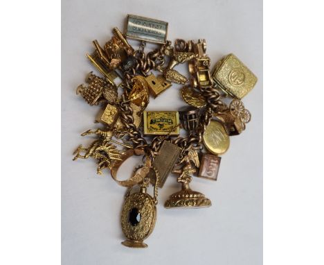 A yellow metal charm bracelet, with oval twisted links set with numerous yellow metal charms including a sled, chapel, poodle