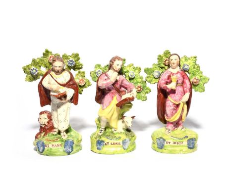 Three Staffordshire figures of the Evangelists, 19th century, depicting St Mark, St Luke and St John, the first with a lion, 