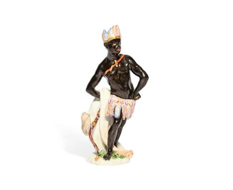 A Meissen figure of Africa, c.1750, wearing a feathered skirt and headdress, his hands on his hips with an elephant hide held