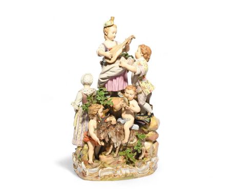A large Meissen figure group of country revellers, 19th century, a young girl standing atop a rocky outcrop and playing a str