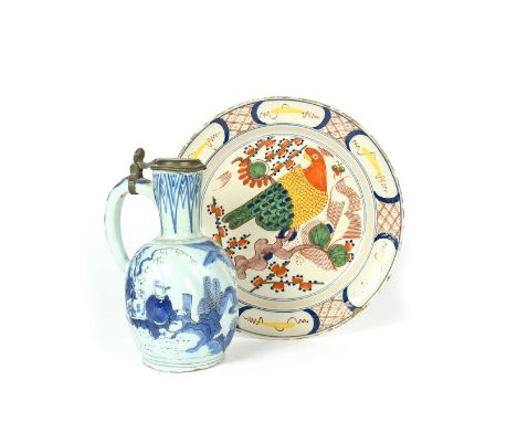 A Delft charger, 18th century, brightly enamelled with a parrot perched on a branch within a panelled rim, and a German faïen