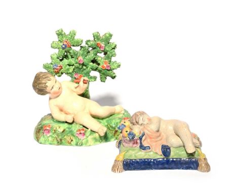Two Staffordshire figures of putti, 19th century, one recumbent on a grassy base before flowering bocage, the other sleeping 