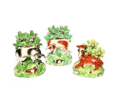 A pair of Salt (Staffordshire) pearlware figures of cows, 1st half 19th century, each standing on a rocky outcrop with a recu