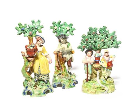 A pair of Staffordshire pearlware figures of gardeners, 1st half 19th century, each standing beneath tall flowering bocage, s