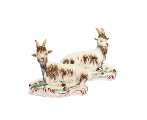 A pair of Derby figures of goats, c.1765, each recumbent with one foreleg outstretched and heads slightly turned, raised on l