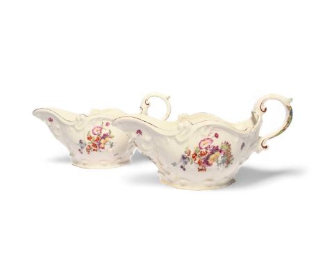 A pair of Longton Hall sauceboats, c.1755, the generous forms with moulded scrolls and painted with flower sprays in the 'Tre