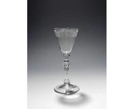 A Newcastle light baluster glass or goblet, c.1740, the round funnel bowl engraved with a continuous formal foliate scroll bo