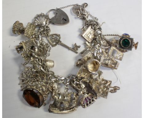 A silver charm bracelet with a large quantity of charms to include cuckoo clock, Victorian lamp, kangaroo etc, approx 2.9ozt.