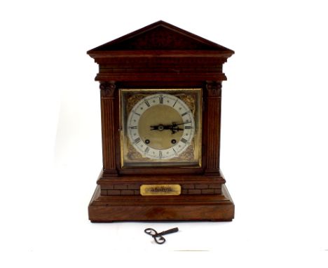A late Victorian architectural oak bracket clock, the brass dial set with Roman numerals and silvered chapter ring, flanked o
