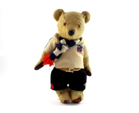 A vintage early/mid-20th century straw-filled Teddy bear with leather paws and feet, glass eyes, in a handmade Bolton Wandere
