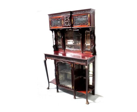 An Edwardian mahogany Empire cabinet, carved frieze above two glazed doors with central carved panel decoration over triple m