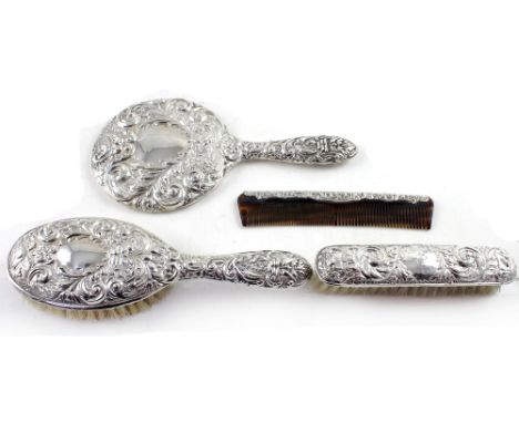 An Elizabeth II hallmarked silver four piece dressing table set comprising hand mirror, ladies' and gent's brush and a silver