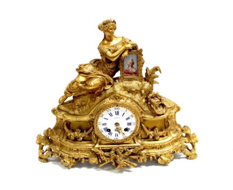 A French ormolu eight-day mantel clock, seated female artist leaning against a Sèvres-style ceramic panel in gilded frame, ov