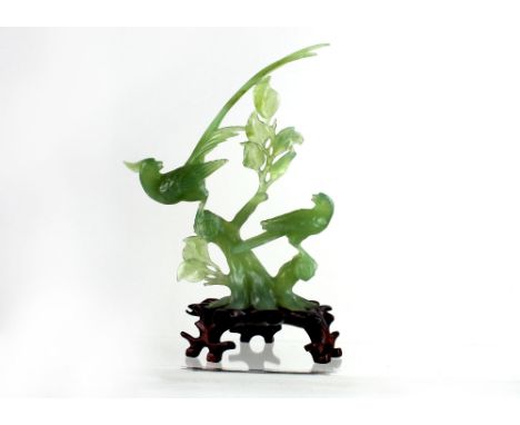 A green jade style carving of birds in flight on a stylised hardwood base, height 21cm.