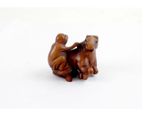 A Japanese carved fruitwood netsuke of a monkey.