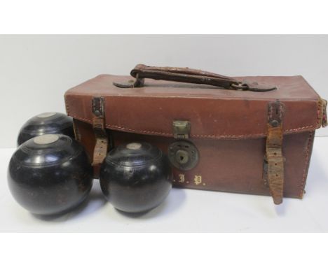 A vintage brown case containing a set of three bowling balls.