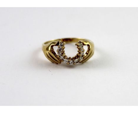 A 9ct yellow gold ladies' dress ring in the form of a pair of slender hands holding a horseshoe set with small white stones, 