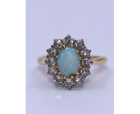 An opal and diamond cluster ring, claw set oval opal cabochon (some wear) within border of twelve brilliant-cut diamonds, tot