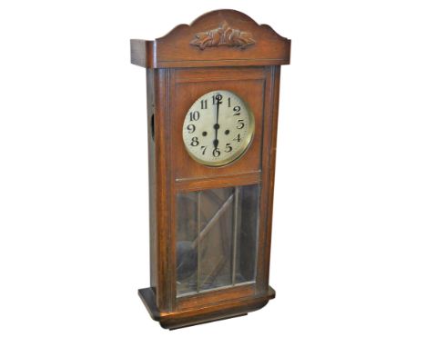 An early 20thC oak cased wall clock, with silvered dial bearing Arabic numerals, eight day movement with coil strike, the cas
