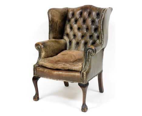 An early 20thC tan leather wing back armchair, with button back and stud detailing to top, on oak cabriole legs terminating i