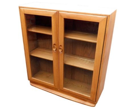 An Ercol light elm bookcase, with a pair of glazed doors enclosing two shelves, raised on a plinth base, 100cm high, 92cm wid