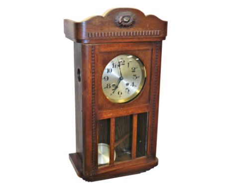 An early 20thC oak cased wall clock, with silvered dial bearing Arabic numerals, eight day movement with coil strike, the cas