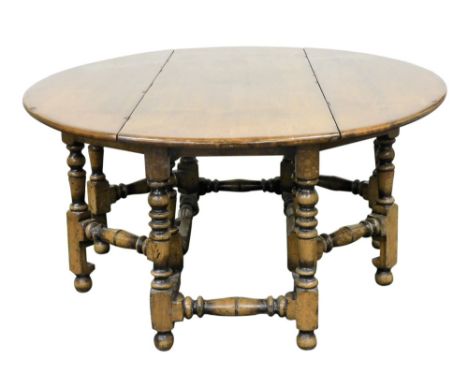 A Jacobean style solid oak and elm wake dining table, with double turned gate leg action, united by turned stretchers, 77cm h