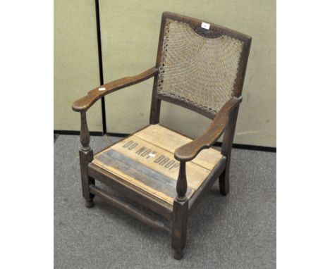 A,low oak bergere backed armchair with a carved half flower motif finial, the seat replaced with modern wood planks, height 7