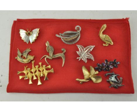 Ten assorted costume jewellery brooches including a mother of pearl butterfly, a pelican and a sailing boat